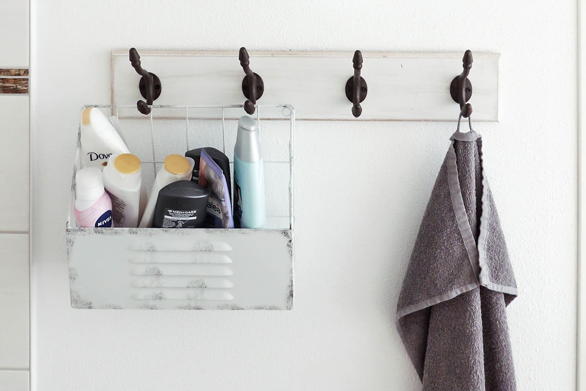 Shower caddy and towel on a hanger in a bathroom.