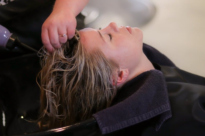 woman getting hair washed by salon suite stylist